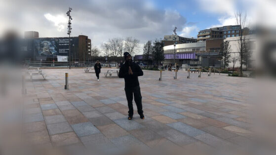 JClay with praying hands on a street in London