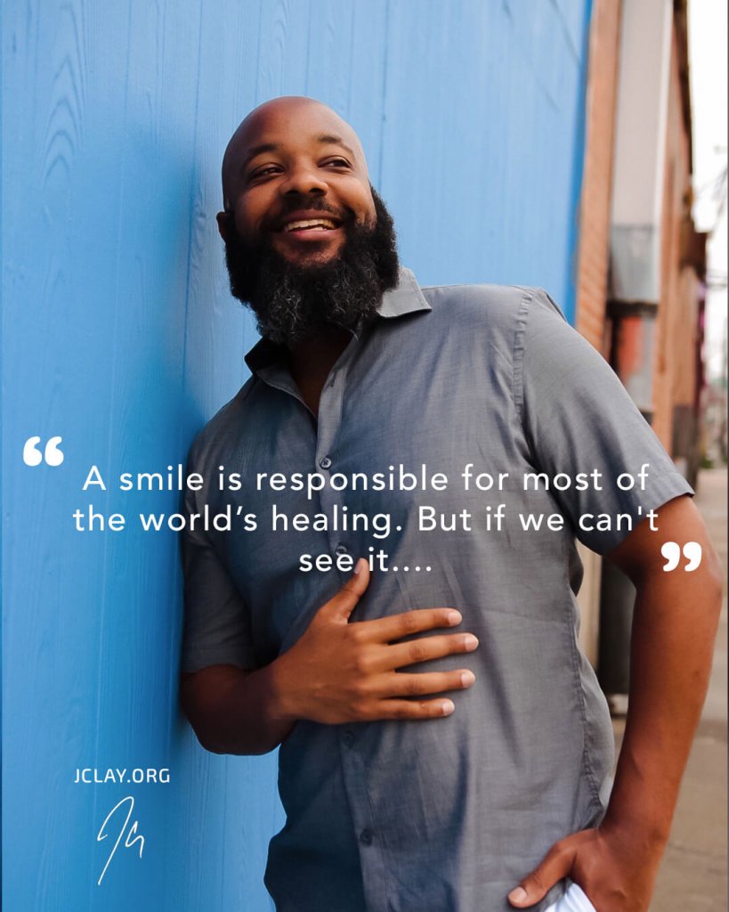 inspirational quote by jclay in front of blue wall with him smiling beard bald head